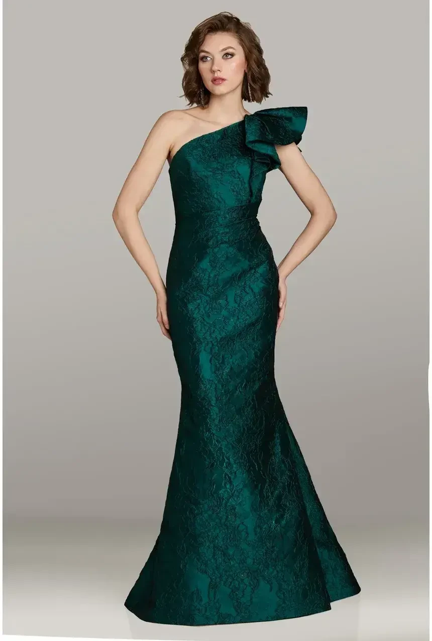 A woman in a one-shoulder, dark green, textured gown with a side bow poses against a neutral background, conveying elegance and sophistication.