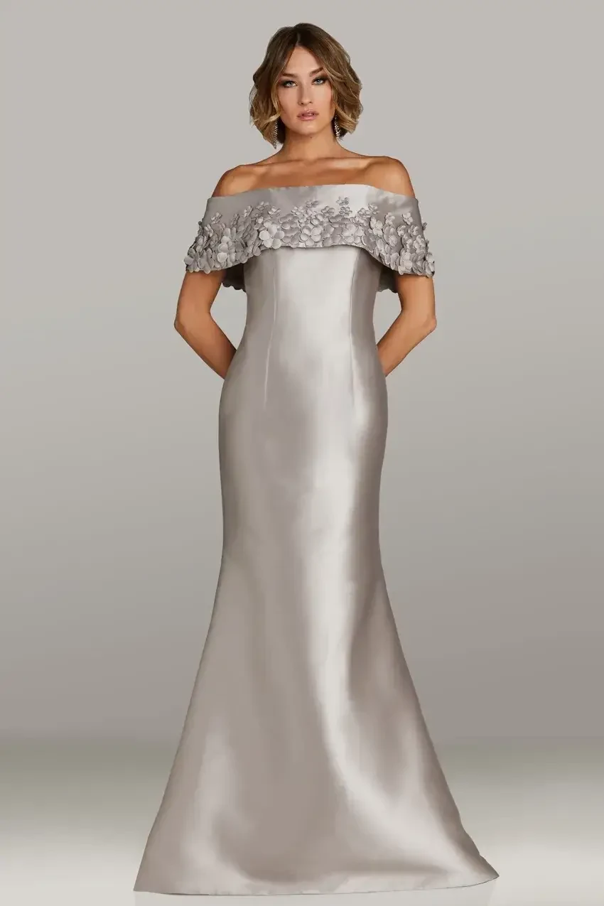 model is wearing an off the shoulder silver evening gown by feriani couture and gia franco