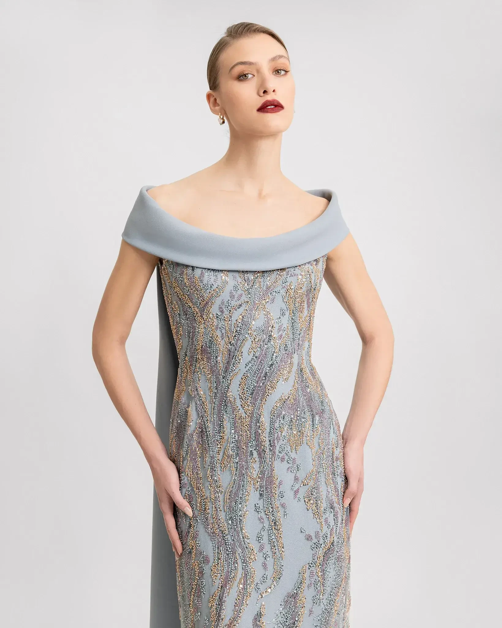 model is wearing an off the shoulder grey evening gown by gemy maalouf