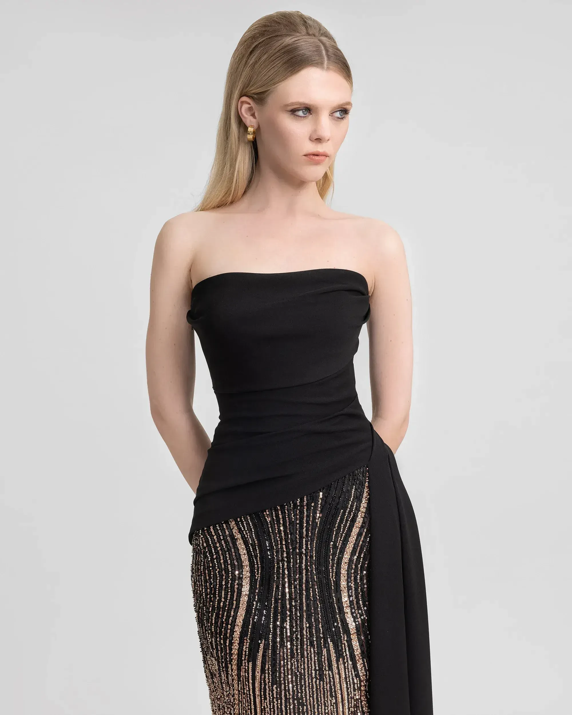 model is wearing a sleek black strapless evening gown by gemy maalouf