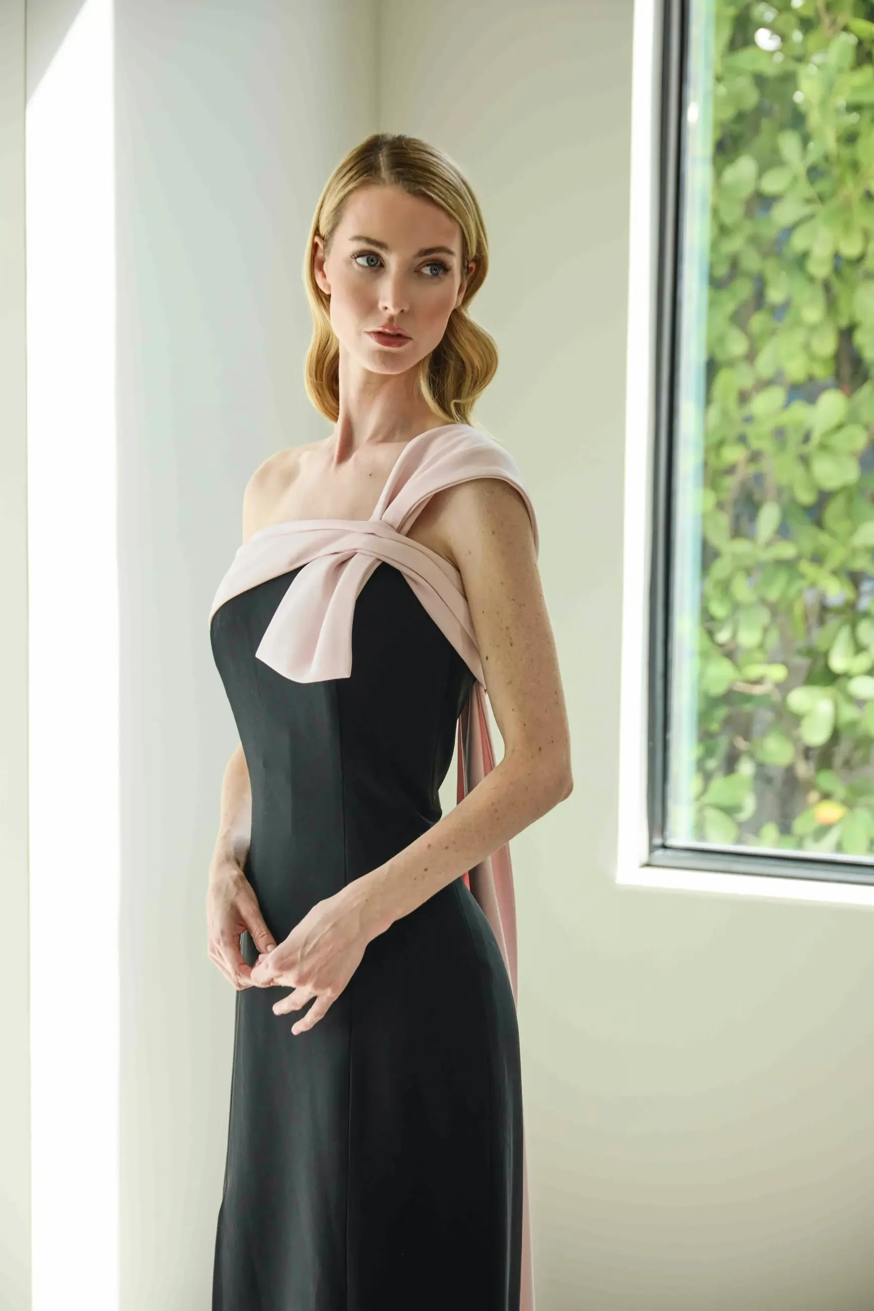 model is wearing a sleek light pink and black evening gown