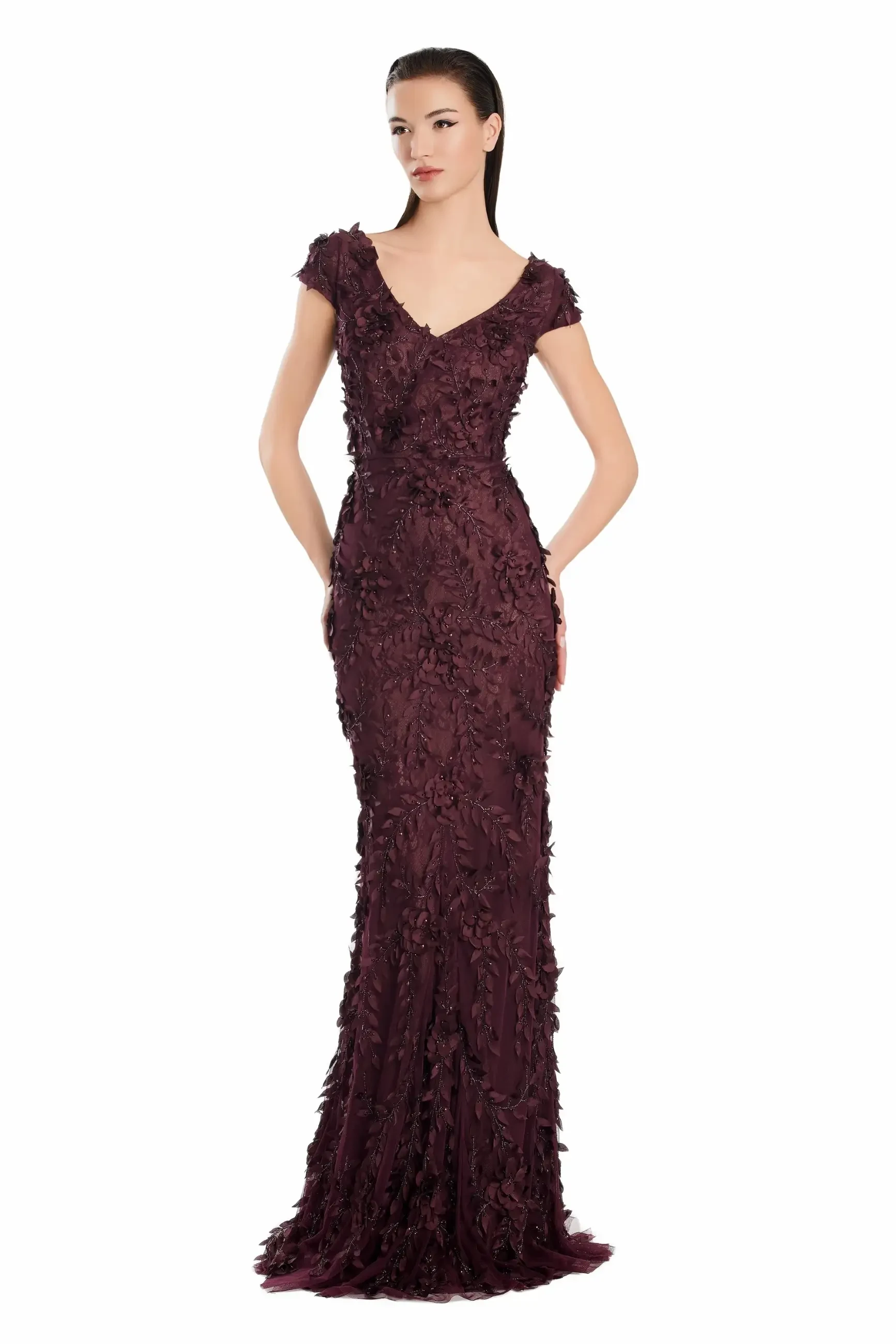 A woman in a fitted, dark burgundy gown stands against a white background. The dress features intricate floral embellishments, exuding elegance and sophistication.