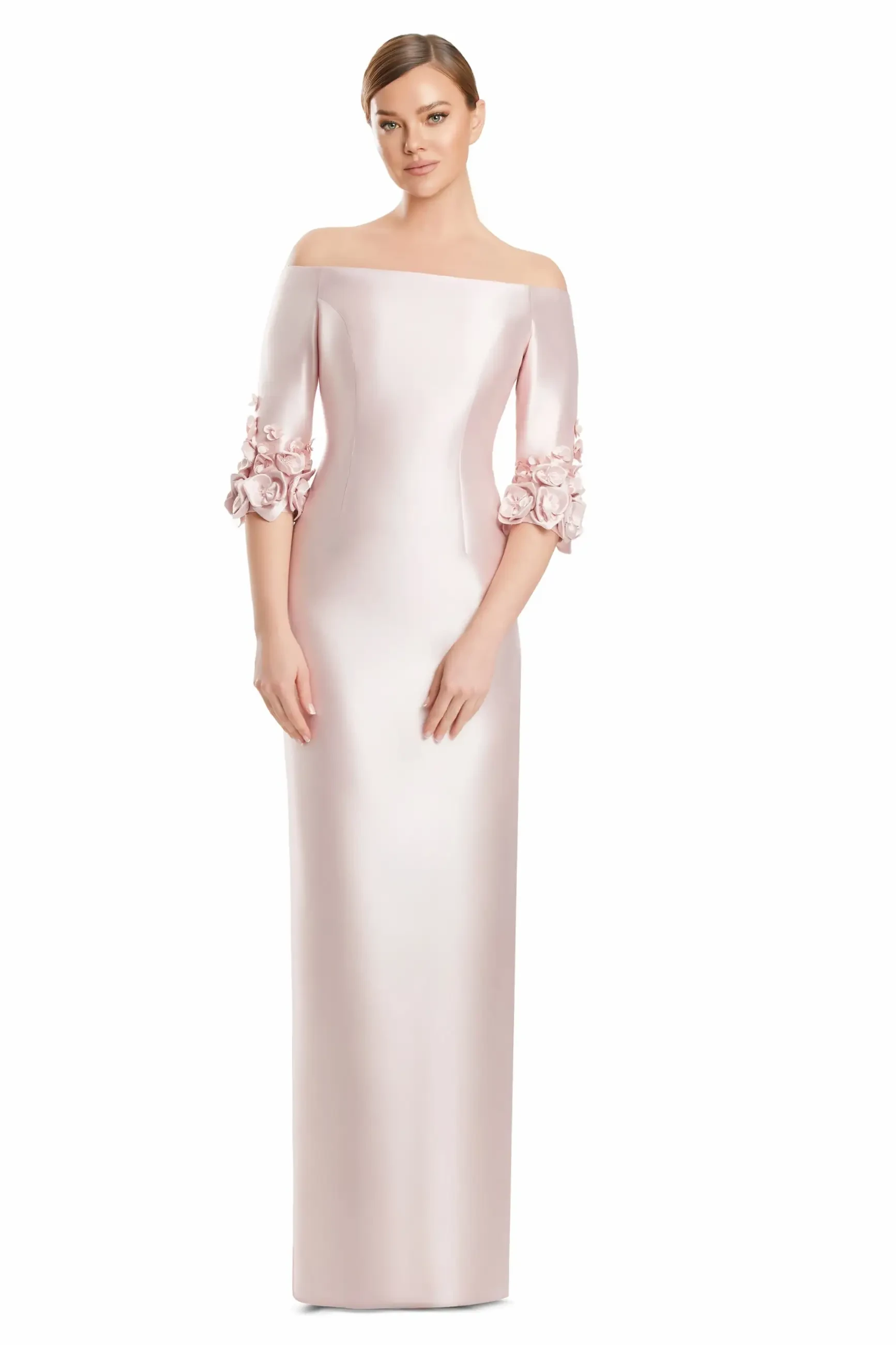 Woman in an elegant, off-shoulder, light pink gown, featuring 3D floral details on elbow-length sleeves. She stands confidently, exuding a graceful and poised vibe.