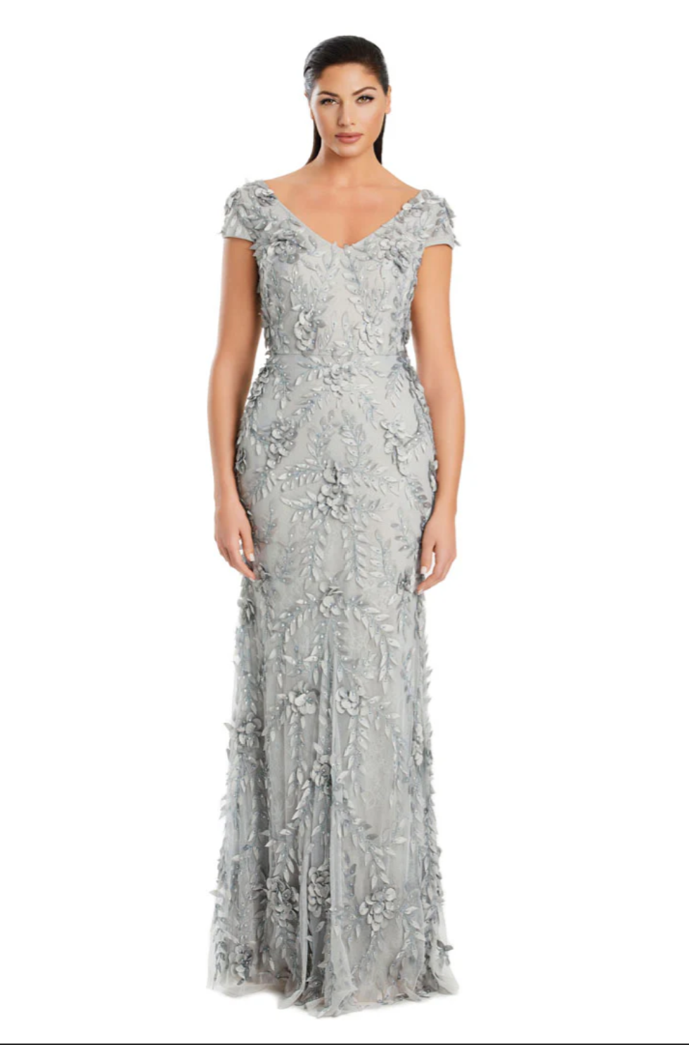 A woman in an elegant, form-fitting gray gown with intricate floral embroidery stands on a white background. She exudes confidence and poise.