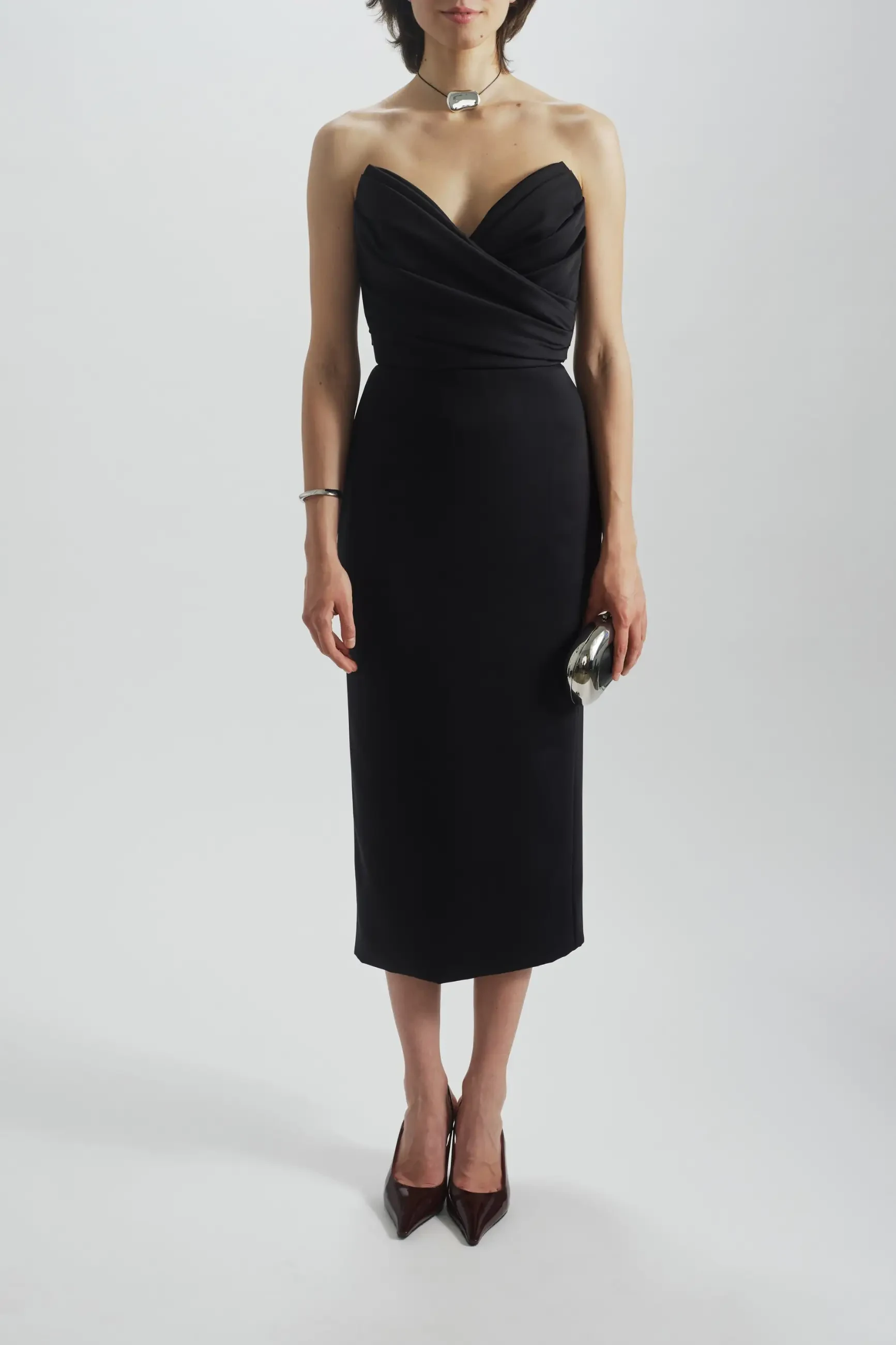 model is wearing a strapless black tea length cocktail gown by amsale