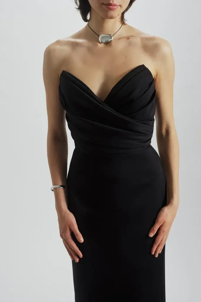 model is wearing a strapless black tea length cocktail gown by amsale