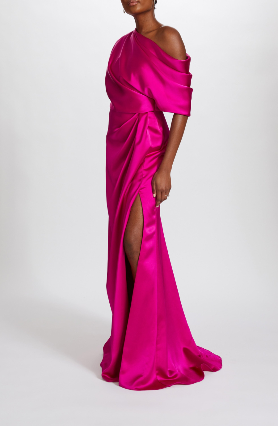 A person wears an elegant, vibrant pink satin gown with an off-the-shoulder design and a high slit, conveying a sophisticated and glamorous tone.