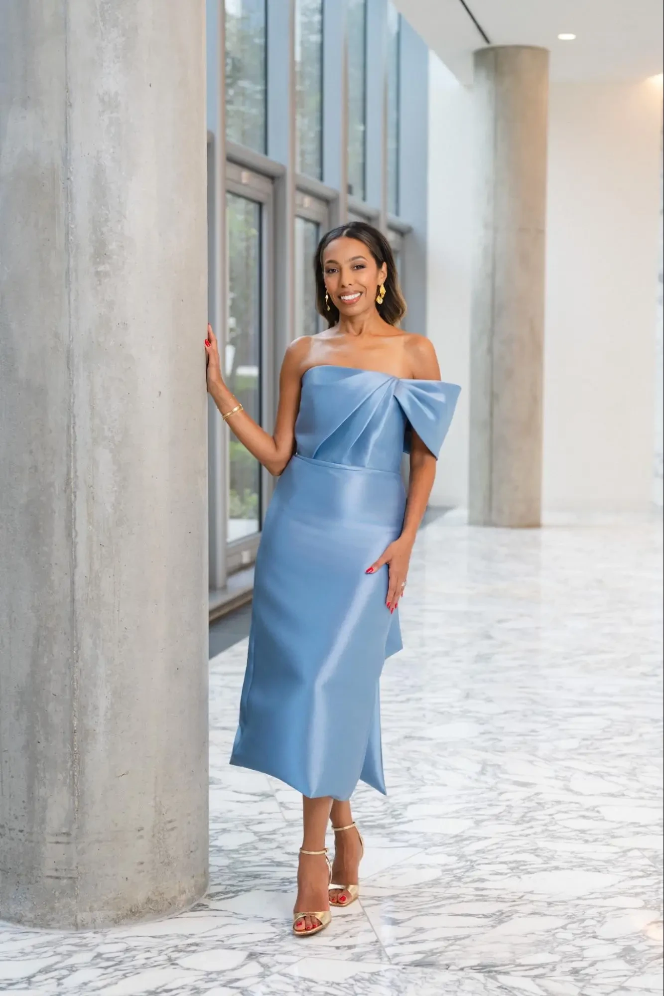model is wearing a knee length asymmetrical neckline light blue gown
