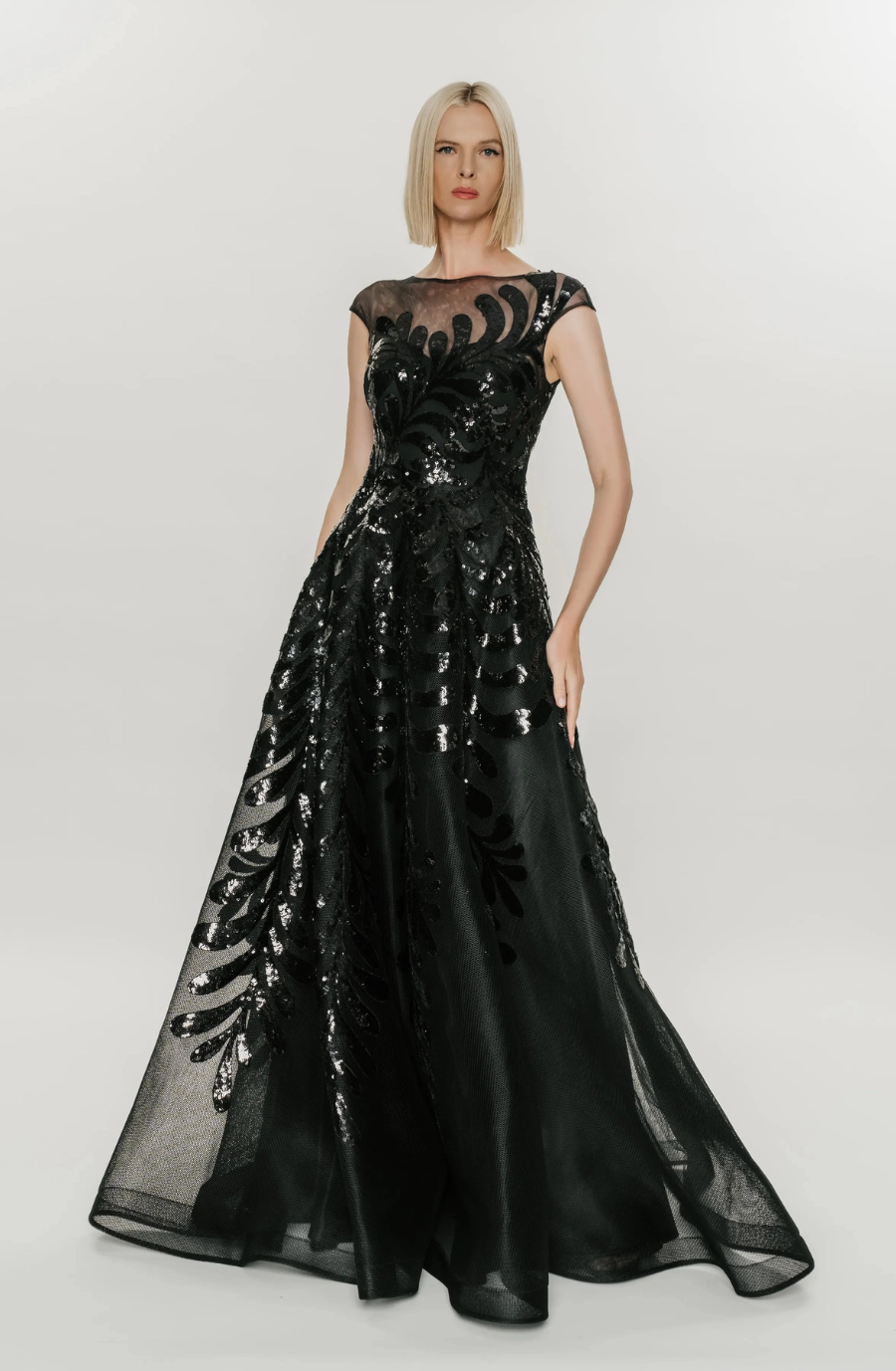 model is wearing a black lace a-line cap sleeve evening gown