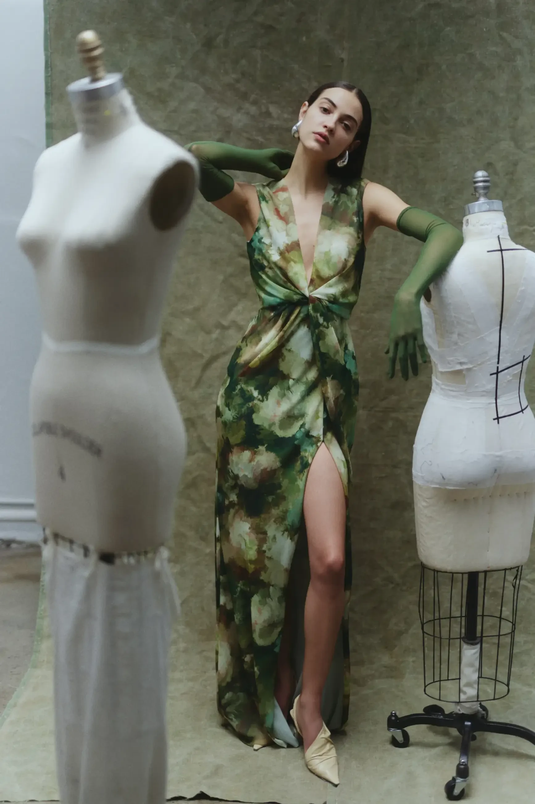 model is wearing a green evening gown with a slit and plunging neckline